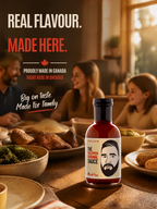 A bottle of Phlippens Original Sauce is prominently displayed in the foreground on a wooden dining table, with a family blurred in the background at a dinner table. The image features marketing text at the top: 'REAL FLAVOUR.